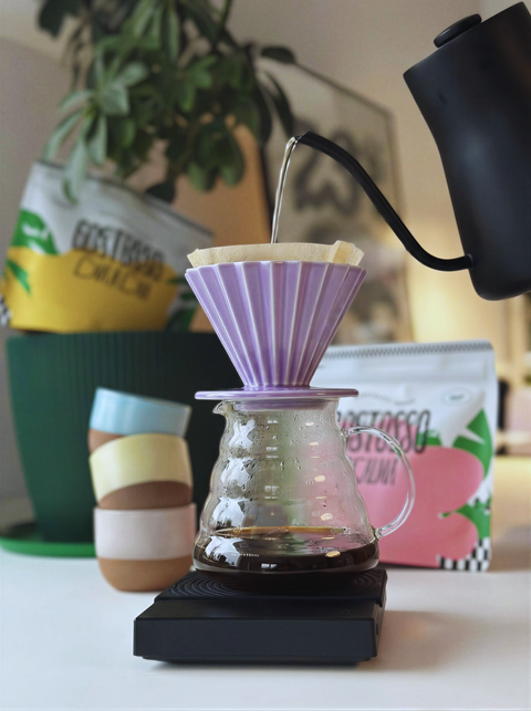 Coffee brewing process with a glass carafe and purple filter on a blurred background